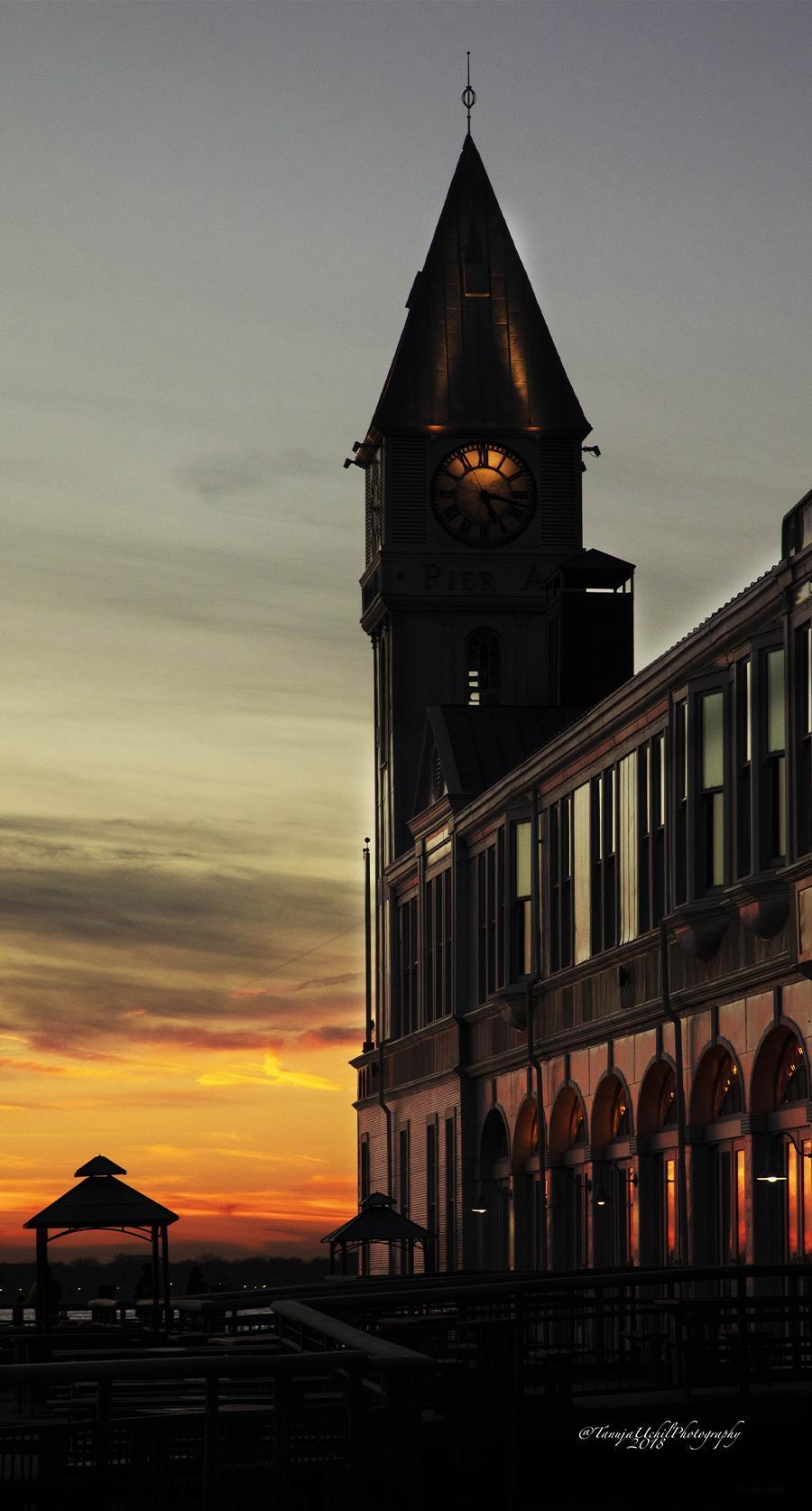 scenery of a clock tower with a sunset in the background