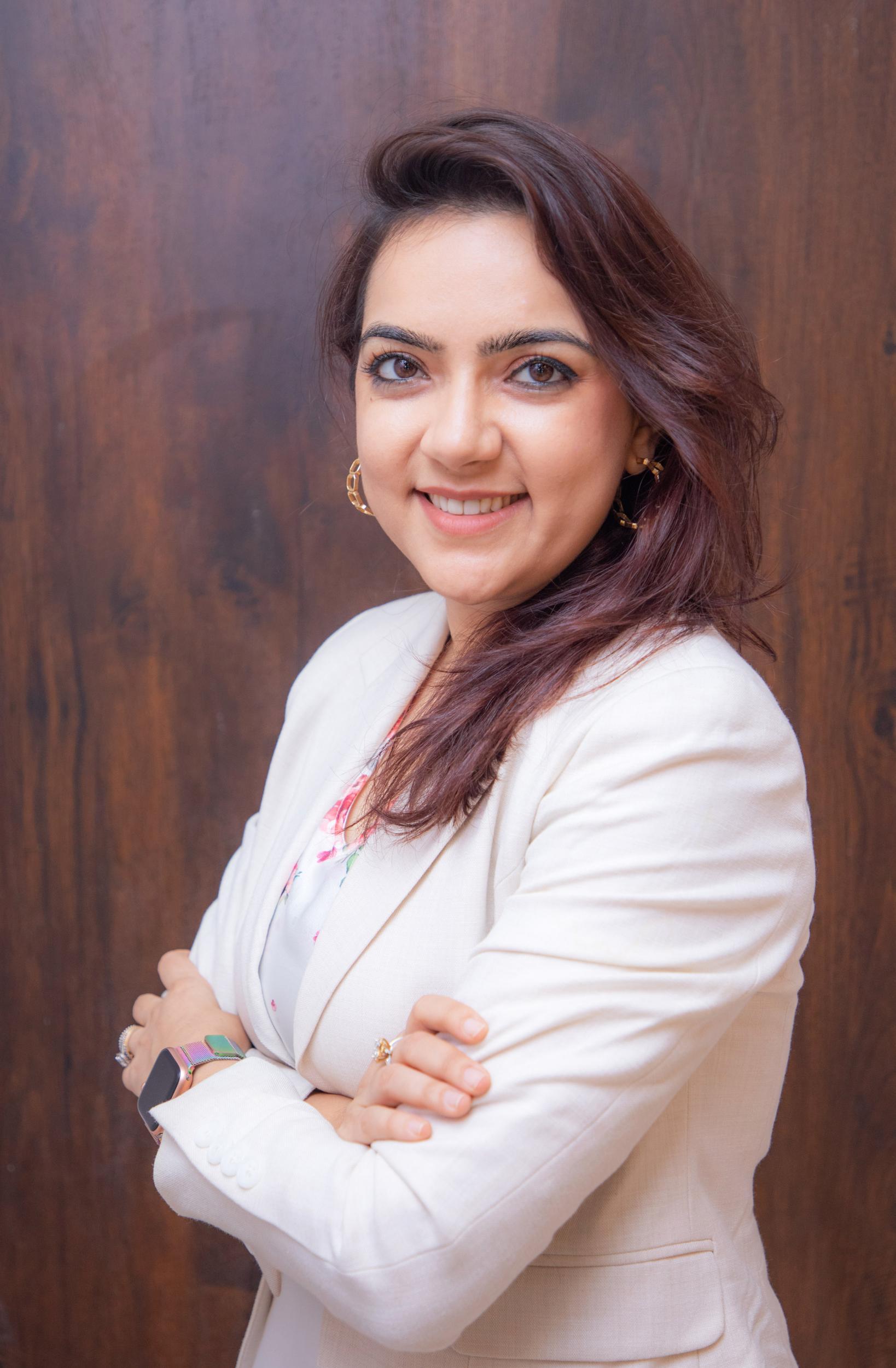 corporate headshot of a woman in a white suit and gold earrings