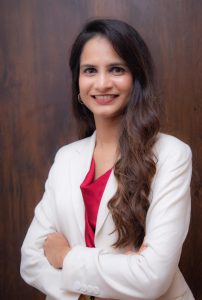 corporate headshot of a woman in a white jacket and red shirt