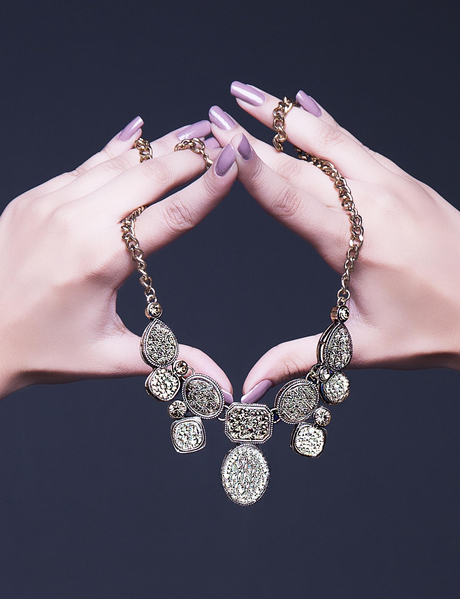 image of a woman's hands holding a necklace with a heart shaped charm