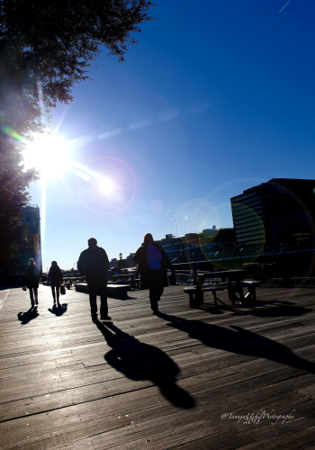 abstract pic of people walking on a boardwalk with a sun in the background