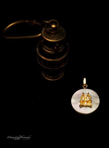 product shoot of a gold buddha charm on a black background