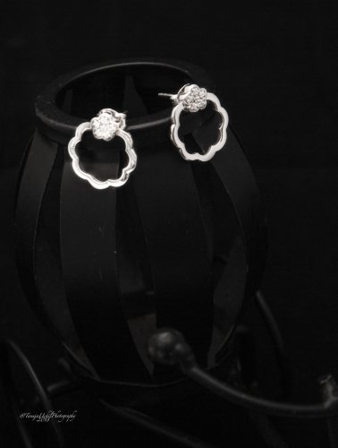 product shoot of a pair of silver earrings on a black background