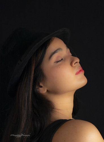 portrait shoot of a woman with a hat and a black background