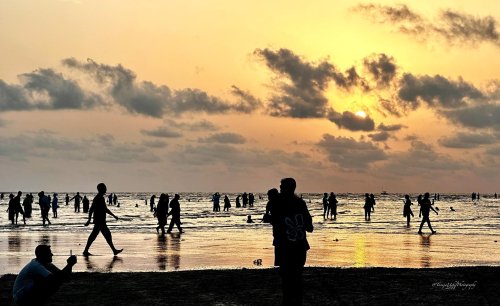scenery of people on the beach at sunset with a cloudy sky