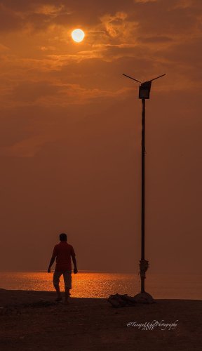 scenery of a man walking on the beach at sunset