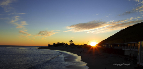 scenery of a beach with a sunset and a few people