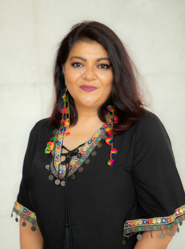 portrait of a woman with a black top and colorful necklace