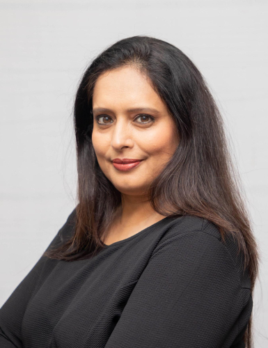 corporate headshot of a woman with long dark hair and a black top