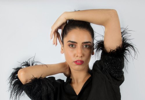 fashion shoot of a woman with a black top and feathered sleeves