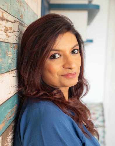 portrait shoot of a woman leaning against a wall with a blue shirt