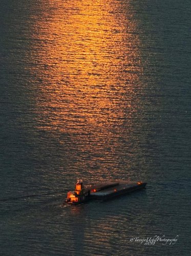 scenery of a boat in the water at sunset with a bright orange light