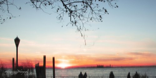 scenery of a sunset over a body of water with a clock tower