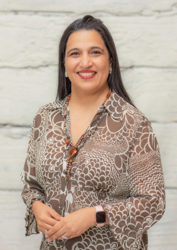 corporate headshot of a woman in a brown and white shirt