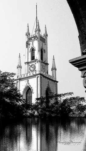 structure of a church with a clock tower and a reflection in the water