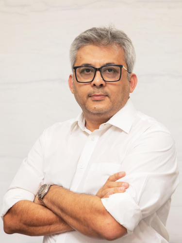 corporate headshot of a man with glasses and a white shirt