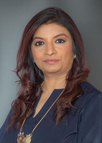 corporate headshot of a woman with long red hair and a necklace