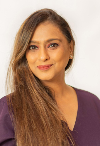 corporate headshot of a woman with long hair and a purple top