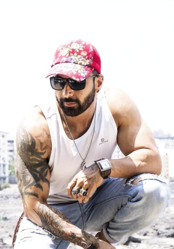 portrait shoot of a man with tattoos and a hat crouching down